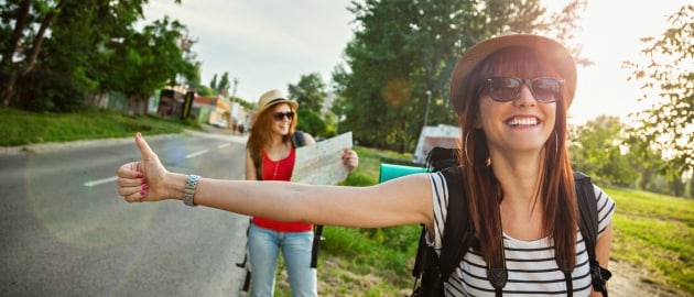 Two Young Tourist Girl Hitchhiking On The Road